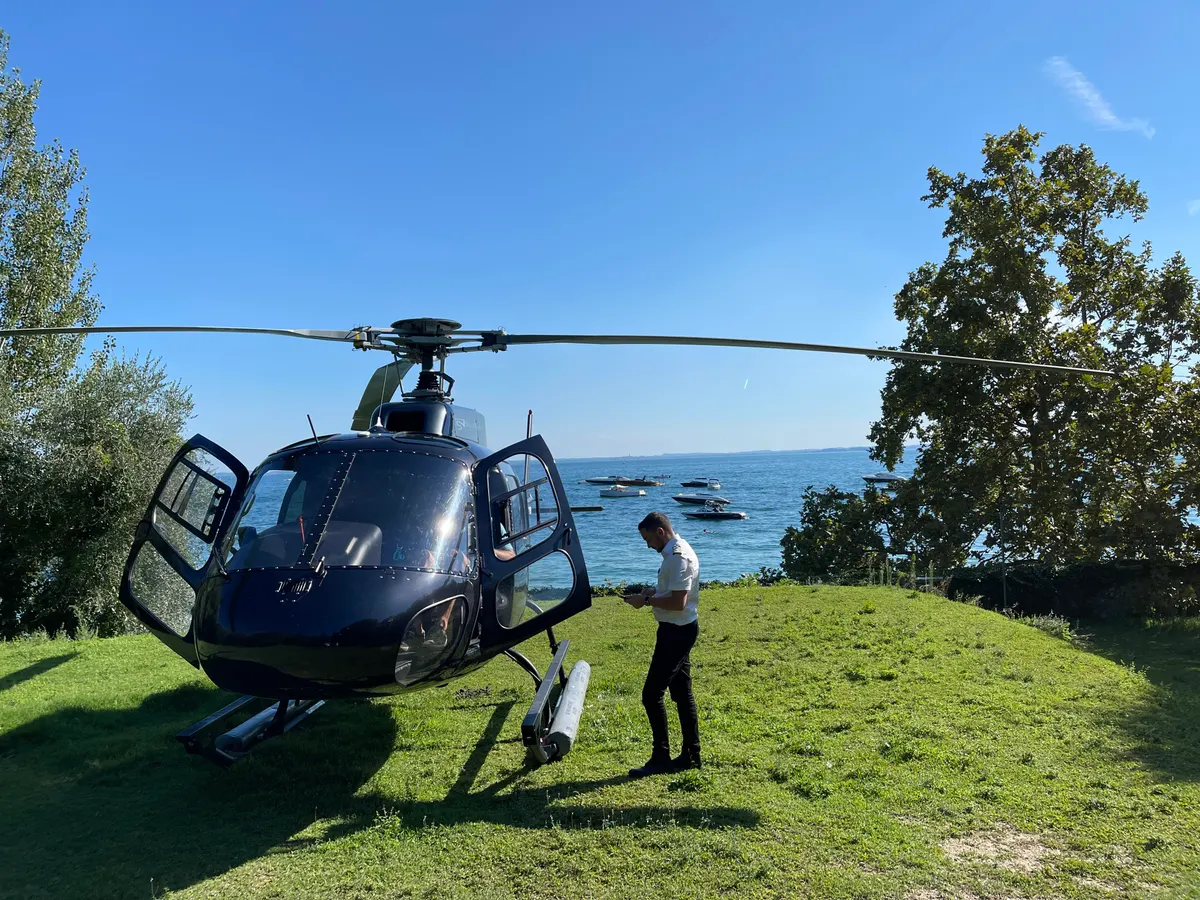 Helikopter auf einer Wiese am Seeufer vor dem Abflug