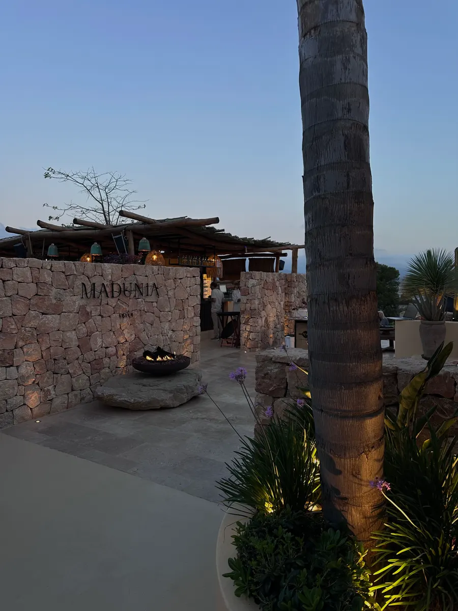 Eingang eines Restaurants auf Ibiza mit Natursteinmauer und Palme am Abend