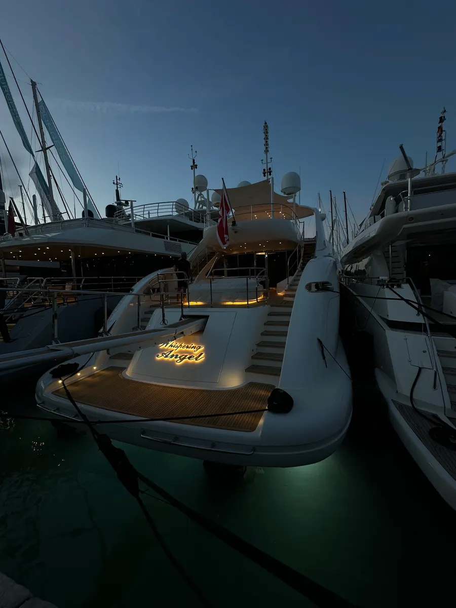 Beleuchtetes Heck einer Motoryacht im Hafen bei Abenddämmerung